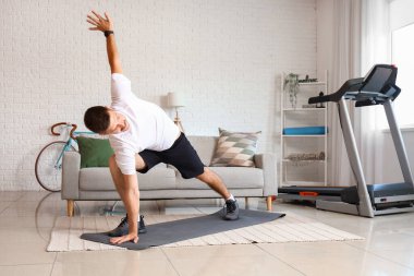 Sportif genç adam evde yoga yapıyor.