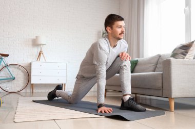 Sportif genç adam evde egzersiz yapıyor.