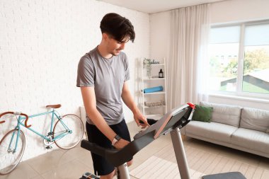 Genç adam evdeki koşu bandında antrenman yapıyor.