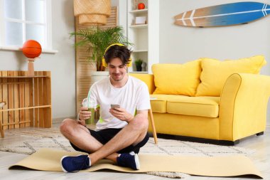 Smoothie 'li sportif genç adam evde müzik dinliyor.
