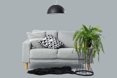 Kanepe, yastık ve gri arka planda saksı olan modern oturma odası.