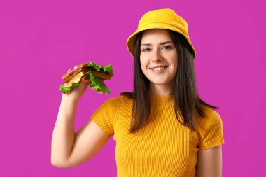 Mor arka planda lezzetli sandviçi olan genç bir kadın.