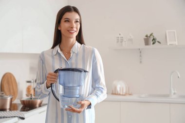 Mutfakta su filtresi olan genç bir kadın.