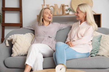 Annesi kanepede oturan ve birlikte vakit geçiren mutlu, genç bir kadın.