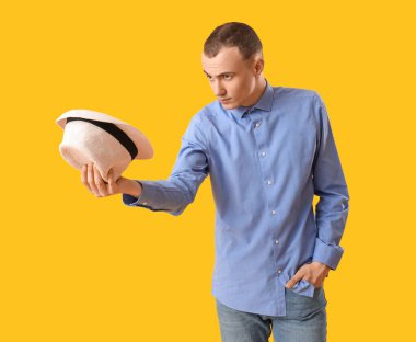 Sarı arka planda şapkalı genç bir adam.