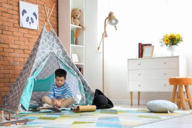 Evde oyun çadırında macera kitabı olan sevimli küçük bir çocuk.