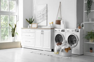 Çamaşır odasının içinde çamaşır makineleri ve kirli çamaşırlarla.