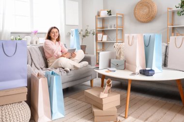 Tablet bilgisayarlı genç bir kadın evde online alışveriş yapıyor.