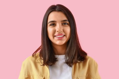 Pembe arka planda sağlıklı dişleri olan gülümseyen genç kadın, yakın plan.