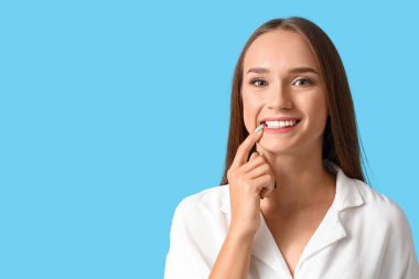 Mavi arka planda sağlıklı dişleri olan gülümseyen genç bir kadın.