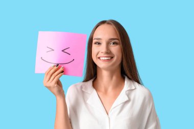 Mavi arka planda kağıt gülüşü olan genç bir kadın.