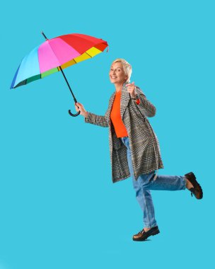 Mavi arka planda şemsiyesi olan güzel olgun bir kadın.