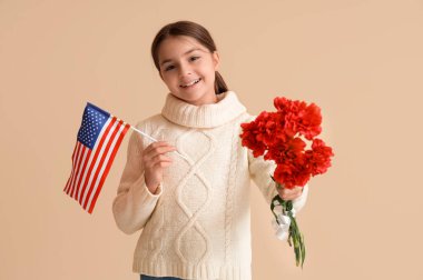 Amerikan bayrağı ve bej arka planda çiçekleri olan küçük bir kız. Gaziler Günü kutlamaları