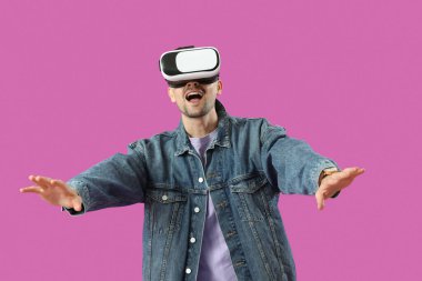 Mor arka planda VR gözlüklü mutlu genç adam.