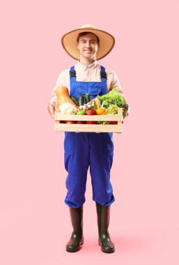 Pembe arka planda taze sebzeleri olan erkek çiftçi.