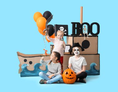 Cadılar Bayramı için mavi arka planda karton gemi taşıyan korsanlar gibi giyinmiş küçük çocuklar.