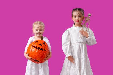 Cadılar Bayramı için giyinmiş küçük kızlar ve mor arka planda balkabağı