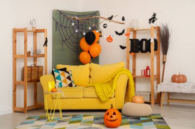 Cadılar Bayramı için dekore edilmiş oturma odasının içi kanepe ve raf üniteleriyle dolu.