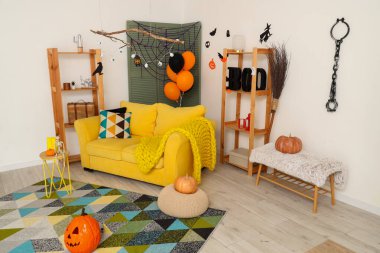 Cadılar Bayramı için dekore edilmiş oturma odasının içi kanepe ve raf üniteleriyle dolu.