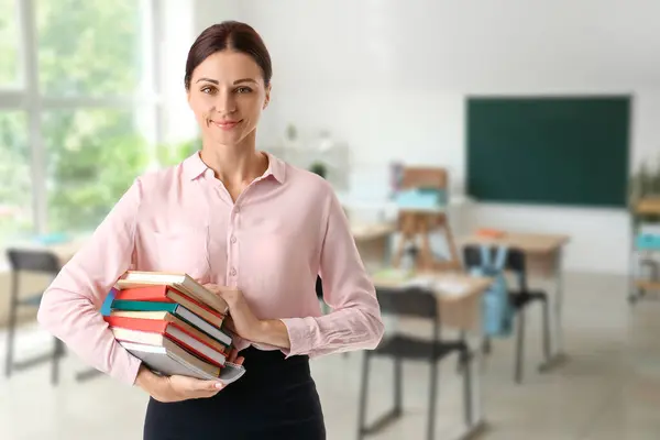Portrait of female teacher with many books in classroom
