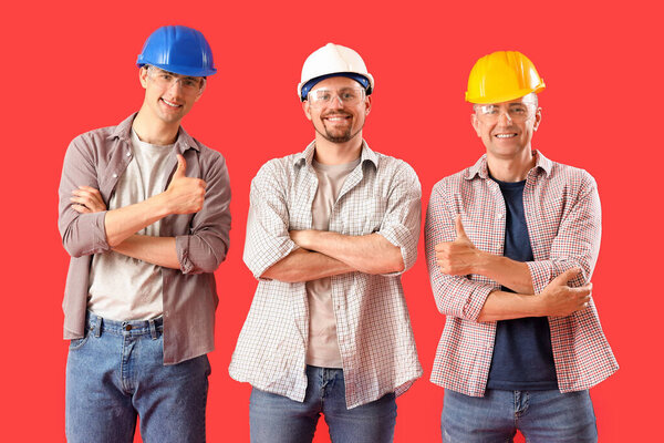 Team of male builders on red background