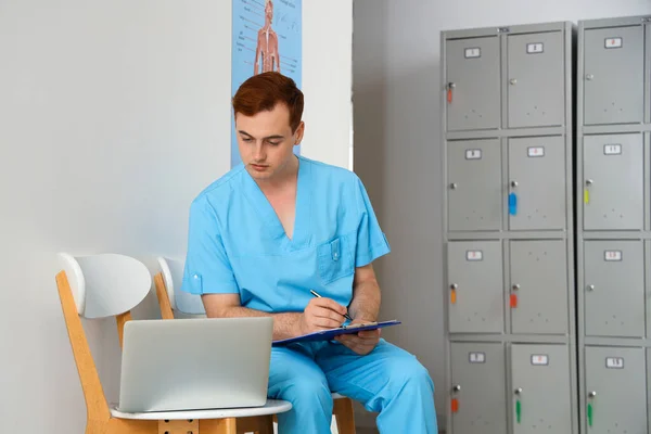 Male medical student studying with laptop at university