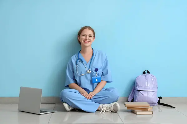 Female medical student studying near blue wall