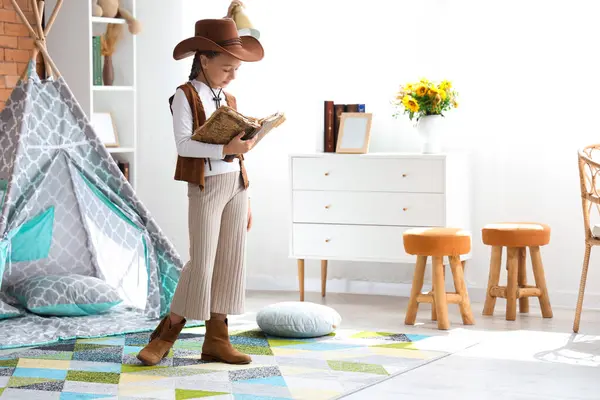 Cute little cowgirl with adventure book at home