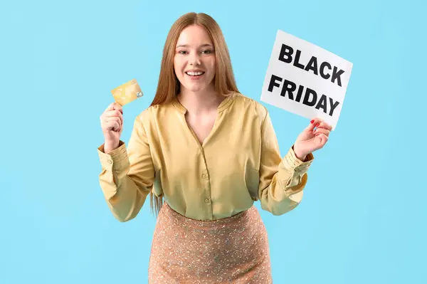 Young woman holding paper with text BLACK FRIDAY and credit card on blue background