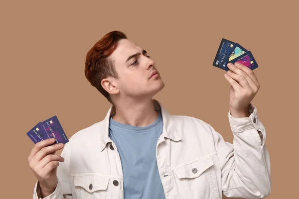 Young man with credit cards on brown background