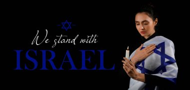 Karanlık arka planda mum ve bayrağı olan dua eden Yahudi kadın. İsrail-Hamas savaşı