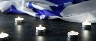 Burning candles and flag of Israel on dark background