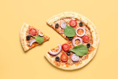 Fesleğenli lezzetli pizza ve sarı arka planda domates.