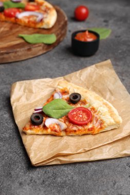 Koyu arkaplanda dilimlenmiş ve lezzetli pizzayla pişirme kağıdı.