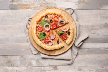 Gri ahşap arka planda fesleğenli ve domatesli lezzetli pizza.