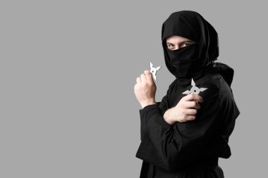 Gri arkaplanda shurikens olan erkek ninja.