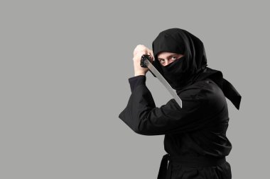 Gri arka planda kılıcı olan erkek ninja.