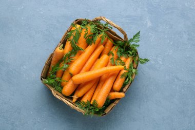 Mavi arka planda taze havuç dolu sepet.