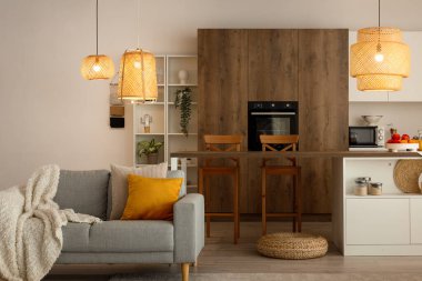 Ada masası, gri kanepe ve parlayan lambalı modern açık mutfak.