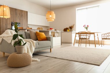 Ada masası, gri kanepe ve parlayan lambalı modern açık mutfak.