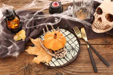 Ahşap arka planda balkabağı şekilli çöreklerle Cadılar Bayramı sofrası.