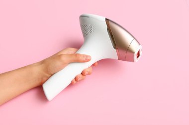 Pembe arka planda modern fotoğraf makinesi olan kadın eli.