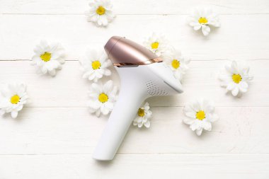 Beyaz ahşap arka planda güzel papatya çiçekleri olan modern fotoepilatör.