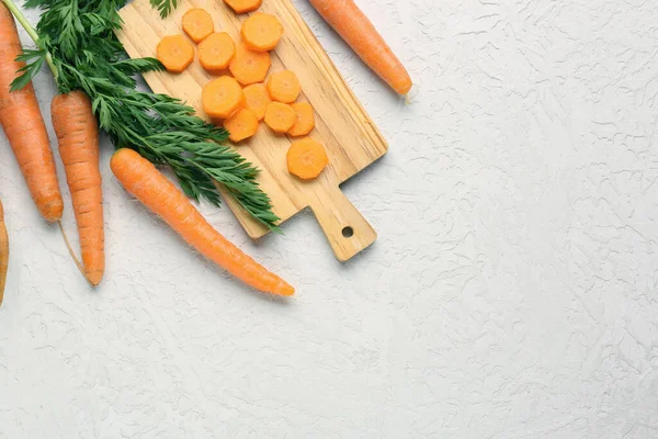 Board with slices of fresh carrots on white background