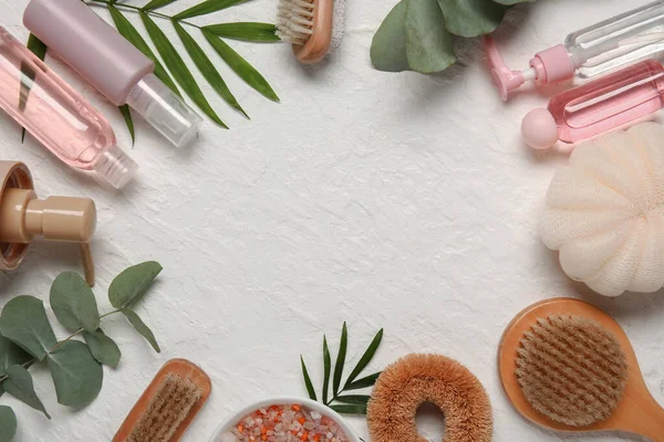 Frame made of bath supplies, cosmetics and eucalyptus branches on light background