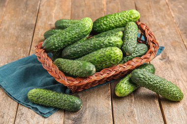 Tahta arka planda taze salatalıklı hasır sepet.