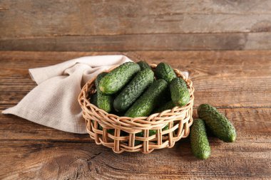 Ahşap zemin üzerinde taze salatalıklar olan hasır bir kase.