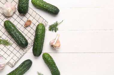 Beyaz ahşap arka planda taze salatalık, sarımsak ve dereotu.
