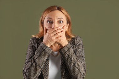 Yeşil arka plandaki korkmuş olgun kadın.