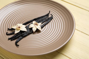 Aromatik vanilyalı tabaklar ve sarı ahşap arka planda çiçekler.